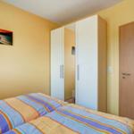 Zimmer mit zwei Betten, Kleiderschrank und Tür. Wandbild an der Wand.