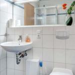 Badezimmer mit Waschbecken, Spiegel, Toilette und Dusche