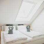 Schlafzimmer mit Dachschrägen, Dachfenster und Bett mit zwei Handtuchschwanen.