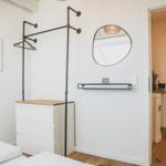 Schlafzimmer mit Kleiderständer, Spiegel und Schrank. Durchgang in angrenzenden Raum.