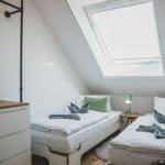 Zwei Einzelbetten unter Dachschrägen mit Dachfenster und Nachttisch.
