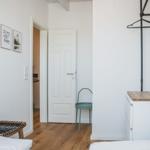 Schlafzimmer mit Holzboden, Bett, Kleiderschrank und Wandbildern.
