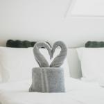 Zwei Handtücher sind als Schwäne geformt und bilden ein Herz auf dem Bett.