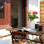 Terrasse mit Holztisch, Stühlen, Blumen und Zeitschrift.