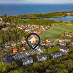Haus in einer grünen Umgebung mit See und Meer im Hintergrund.