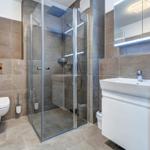 Bad mit Dusche, Waschbecken und Toilette. Wandverkleidung aus Steinoptik.