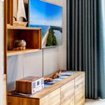 Wohnzimmer mit TV, Holzregal und Fenster mit Vorhang.