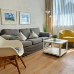 Wohnzimmer mit grauem Sofa, gelber Sessel und weißem Couchtisch.