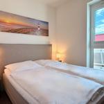 Schlafzimmer mit Bett, Nachttischen und Wandbild. Fenster zeigt Außenbereich.