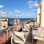 Terrasse mit Sitzgelegenheiten und Meerblick. Glasgeländer und moderne Möbel.