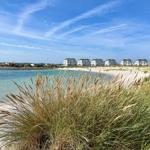 Strand mit Dünenvegetation und Ferienhäusern am Ufer