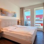 Schlafzimmer mit Doppelbett, Fenster und Balkonblick.
