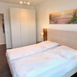 Schlafzimmer mit Doppelbett, Kleiderschrank und Wandbild.