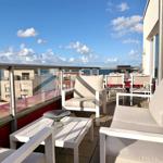 Terrasse mit Sitzgelegenheiten und Blick auf den Himmel und Gebäude.