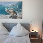 Bedroom with double bed, wall art of a turtle, and two bedside tables.