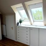 Schlafzimmer mit Dachfenstern, weißem Schrank und Holzboden.
