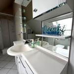 Badezimmer mit Waschbecken, Spiegel und Dusche. Dekorative Aufschrift an Spiegel.