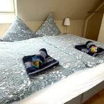 Schlafzimmer mit Doppelbett, gemusterten Kissen und Handtüchern auf dem Bett.