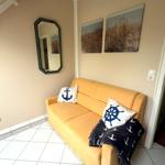 Gelber Sofa mit Kissen und Decke, Wandbilder und Spiegel im Raum.