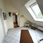 Dachgeschosszimmer mit Dachfenster, Fliesenboden und Sitzgelegenheit.