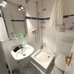 Badezimmer mit Dusche, Waschbecken und Toilette. Weiße Fliesen und Spiegelschrank.