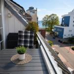 Terrasse mit Tisch, Stuhl und Pflanze. Blick auf Straße, Bäume und Meer.