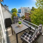 Terrasse mit Tisch, zwei Stühlen und Blick auf Gebäude und Bäume.