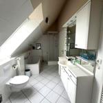 Badezimmer mit Dusche, Badewanne, Waschtisch und Toilette unter Dachschrägen.