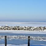 Schneebedeckter Steinschutz am gefrorenen See mit Blick auf den Horizont.