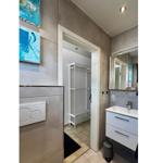 Badezimmer mit Waschbecken, Spiegel und Blick in die Garderobe.