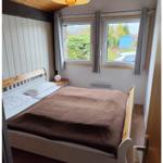 Bedroom with bed, windows, and wooden ceiling.