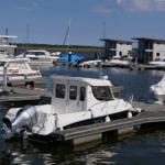 Hafen mit Booten und modernen Wasserhäuschen im Hintergrund.