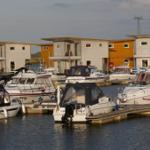 Hafen mit Booten und modernen Stegwohnungen an der Wasserkante.