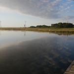 Hafen mit Blick auf ruhiges Wasser und Felder im Hintergrund.