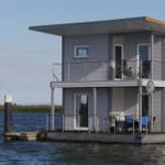 Moderne zweistöckige Bootsvermietung mit Balkon und Terrasse direkt am Wasser.