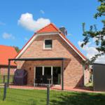 Ein Haus mit rotem Dach und Terrasse mit Garten.