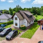 Wohnhaus mit Garten, Parkplatz und Terrasse. Umgeben von Grün und Bäumen.
