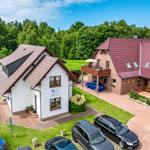 Zwei Häuser mit Garten und Parkplatz. Ein Haus weiß, das andere aus rotem Backstein.