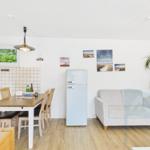 Küche mit Esstisch, Sofa und Kühlschrank. Wandbildern und Pflanze.