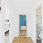 Flur mit Blick in Schlafzimmer, Bad und Raum mit blauer Wand.