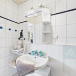 Badezimmer mit Waschbecken, Spiegel und Handtuchständer