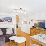 Wohnzimmer mit Sofa, Fernseher und Tisch. Wandbild und Holzmöbel sichtbar.