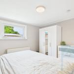 Schlafzimmer mit Bett, Kleiderschrank und Fenster zum Garten.