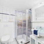 Badezimmer mit Dusche, Waschbecken und Toilette. Glaswand mit winterlichem Motiv.