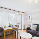 Wohnzimmer mit Sofa, Esstisch und Fenster. Wand mit Streifenmuster.