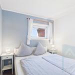 Bedroom with bed, two nightstands, and window with white curtains.