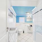 Bathroom with blue ceiling area, toilet, sink, and mirror.