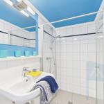 Bathroom with shower, sink, and mirror. Blue ceiling and wall tiles.