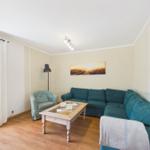 Living room with sofa, armchair, and table. A picture hangs on the wall.