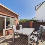 Terrace with table and chairs, adjacent to a house with brick facade.